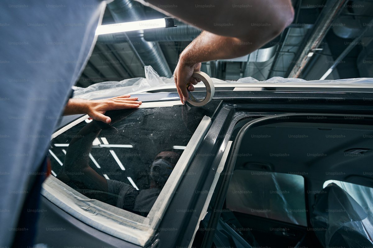 Automotive window tint film installation in progress with professional squeegee