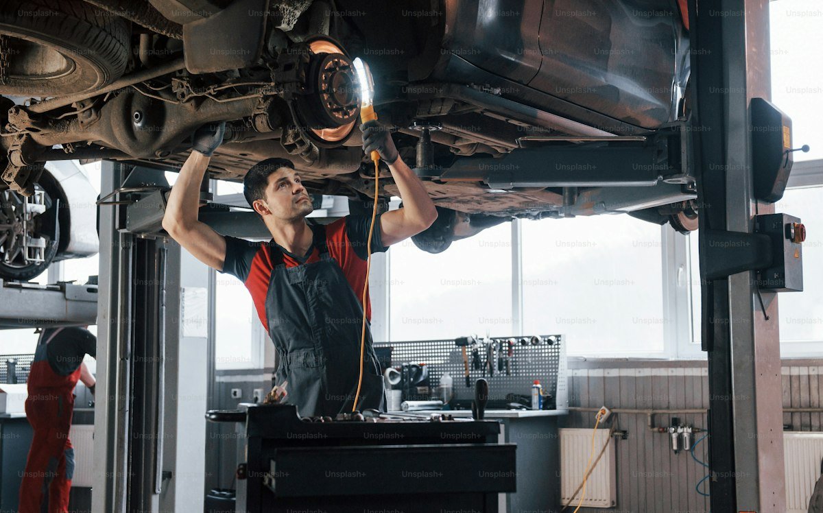 Automotive workshop bay with technician working carefully on vehicle components
